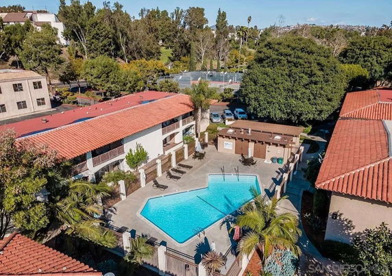 Aerial view of a residential area with a swimming pool surrounded by buildings and trees.