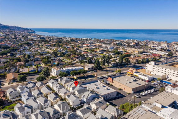 Aerial view of a coastal neighborhood with residential houses and the ocean in the background.