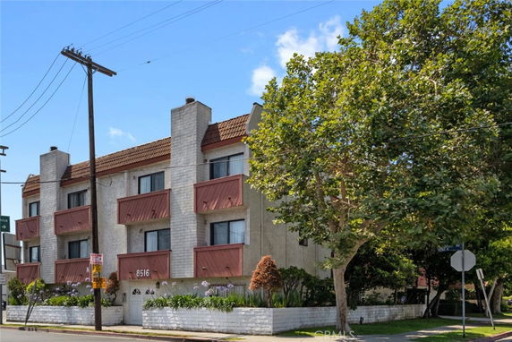 Front view of a three-story building with balconies and a sloped roof.