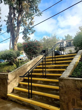 Exterior stairs leading to a residential building with surrounding foliage.