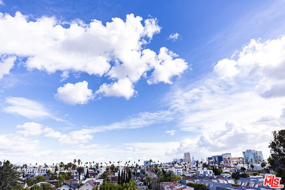 Panoramic view of cityscape under a bright blue sky with clouds.