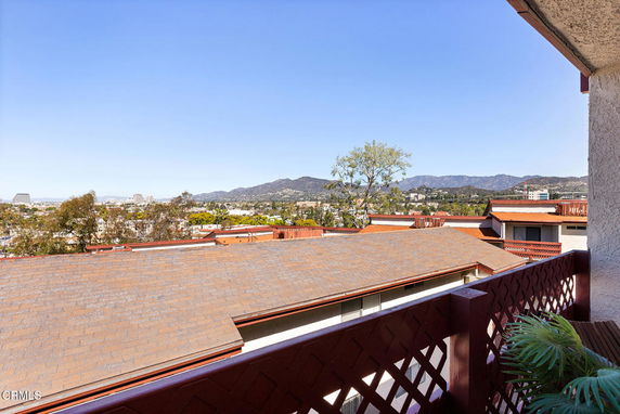 Panoramic view from a building rooftop overlooking the city and mountains.