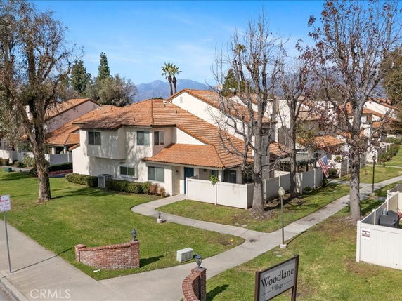 Front view of a two-story townhouse with red-tiled roof and fenced yard.
