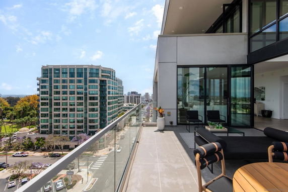 Panoramic view from a modern balcony overlooking urban buildings and a street below.