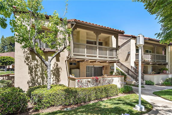 Front view of a two-story residential building with balconies and a walkway.