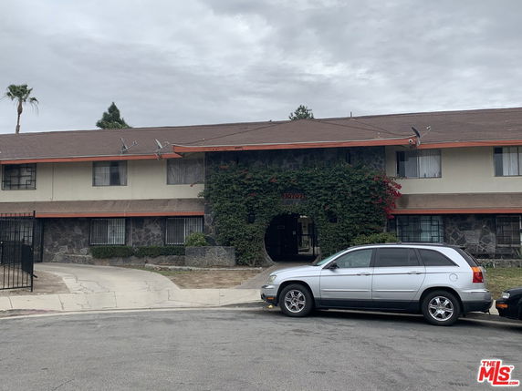 Front view of a two-story residential building with several windows and a gated entrance.
