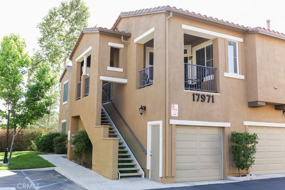 Front view of a two-story building with a staircase leading to the upper level and garages below.