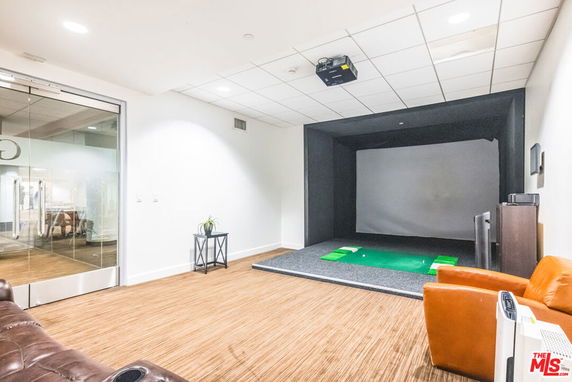 Indoor golf simulation area with seating and projector.
