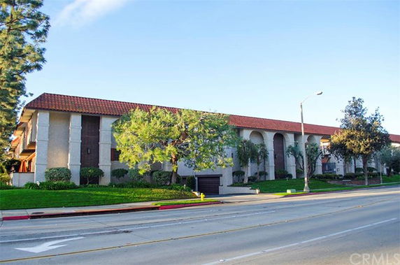 Front view of a two-story building with a red tile roof and arched entryways.