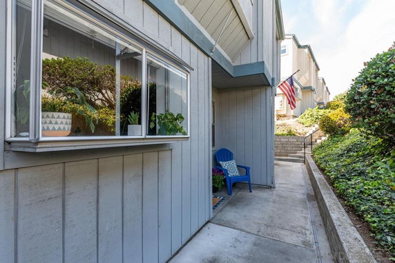 Front view of a house with a small porch and a blue chair.