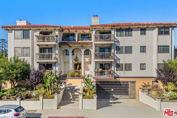 Front view of a multi-story residential building with balconies and a gated entrance.