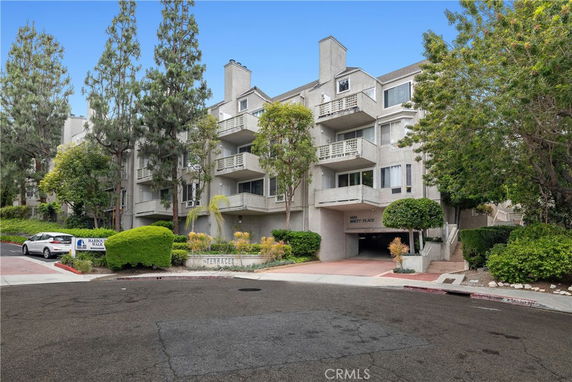 Front view of a multi-story residential building with balconies and a parking entrance.