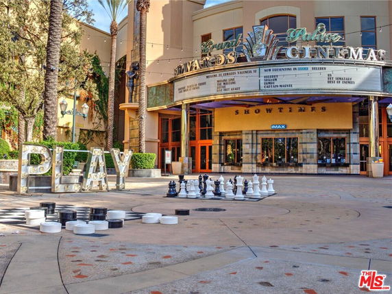 Front view of a cinema with a marquee and large outdoor chess set.