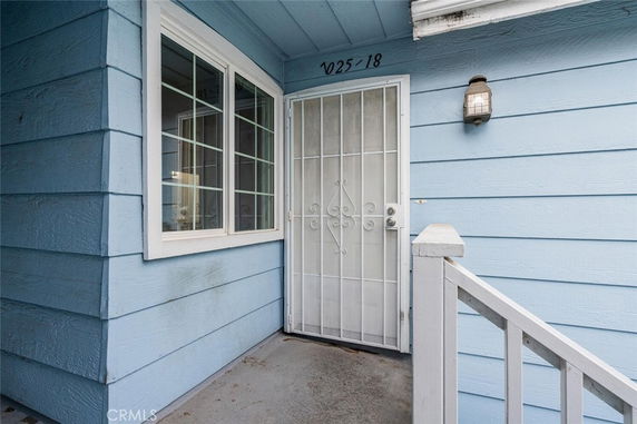 Front view of a house entrance with a metal security door and blue siding.