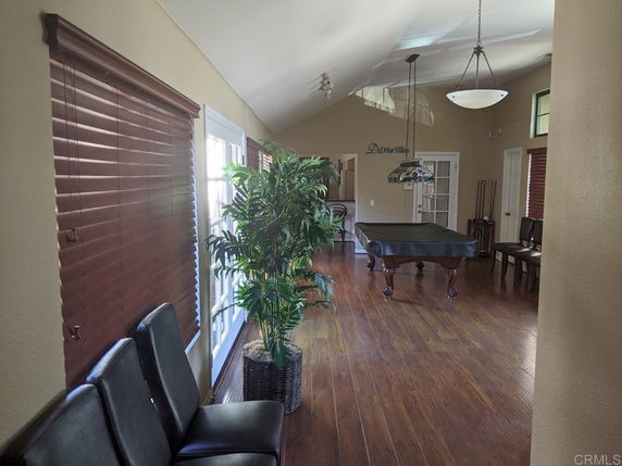 Interior view of a room with a pool table, wooden blinds, and seating.