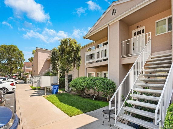 Front view of a multi-unit residential building with stairs leading to an upper floor entrance.