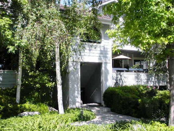 Front view of a two-story building with an entrance partially obscured by trees.