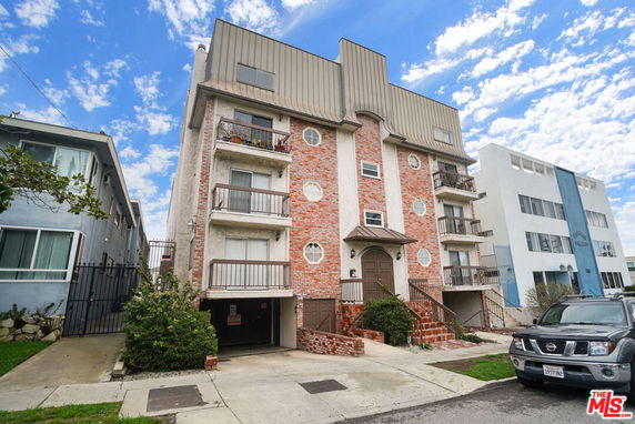 Front view of a multi-story residential building with balconies and a brick facade.