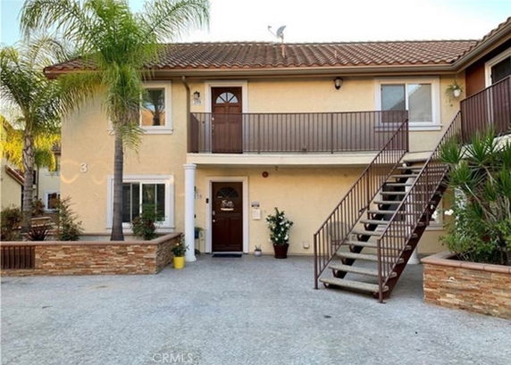 Front view of a two-story house with an external staircase and balcony.