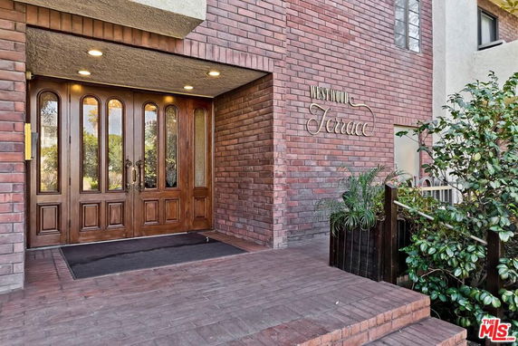Brick exterior entrance of a building with wooden double doors.
