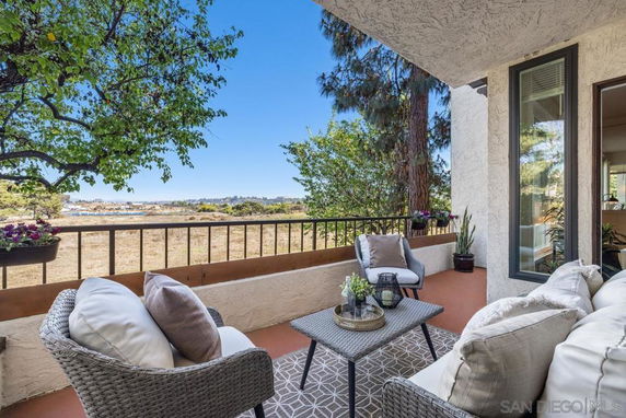 Balcony view with outdoor seating overlooking a scenic landscape and trees.