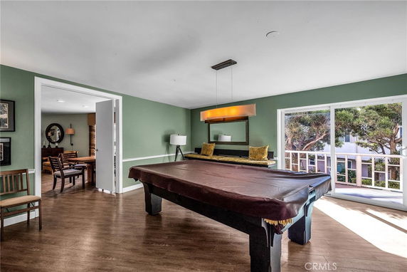 Indoor room with a pool table and large windows overlooking a balcony.