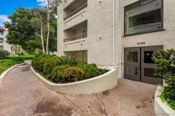 Front view of a multi-story building with balconies and a glass door entrance.