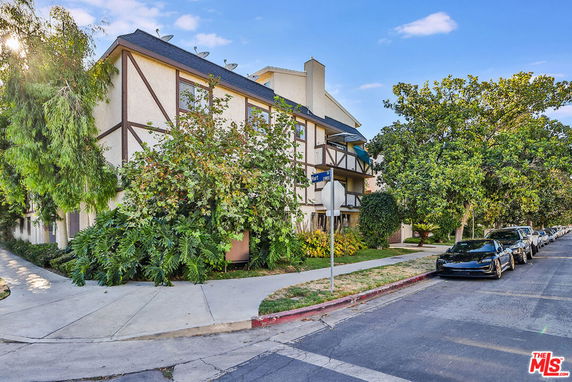 Front view of a multi-story residential building with Tudor-style architecture and green foliage.