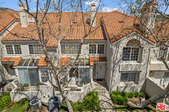 Front view of a two-story townhouse with a red tile roof and multiple windows.