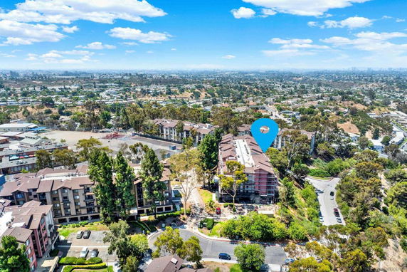 Aerial view of a residential complex with multiple buildings surrounded by greenery and roads.
