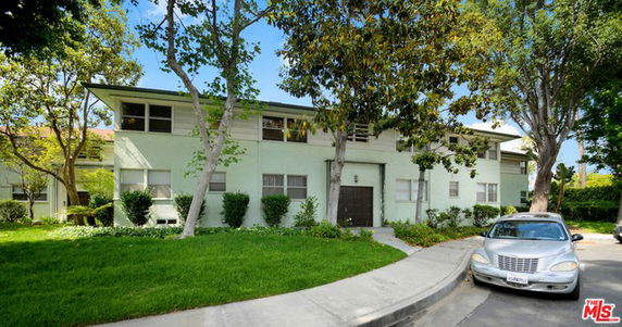 Front view of a two-story residential building with a flat roof and multiple windows.