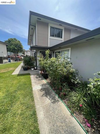 Front view of a two-story house with plants and a walkway.