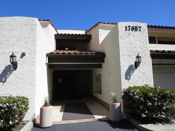 Front view of a two-story building with textured white walls and brown roof tiles.