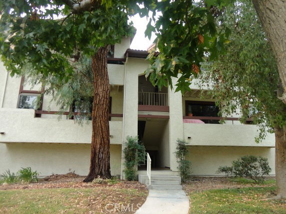 Front view of a two-story residential building with trees and a walkway leading to the entrance.