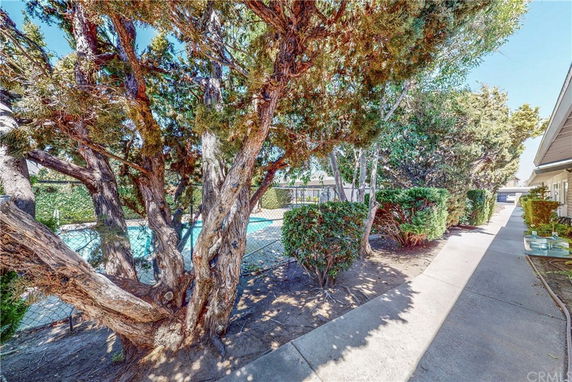 Outdoor swimming pool area surrounded by trees and a walkway.
