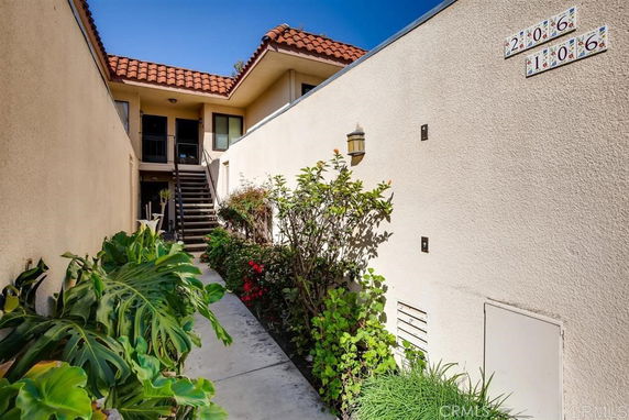 Front view of an apartment entrance with outdoor stairs and plants.