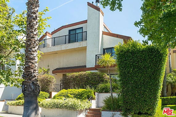 Front view of a multi-story house with balconies and a chimney.