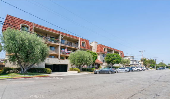 Front view of a multi-story residential building with balconies and a red roof.