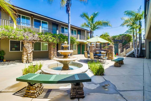 Courtyard view of a building with two floors, featuring a central fountain and outdoor seating.
