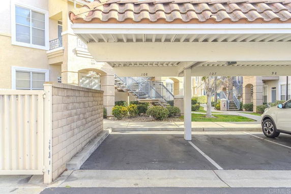 Covered parking area in front of an apartment building.