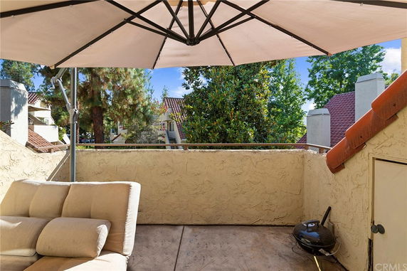 Rooftop area with an umbrella, seating, and a barbecue grill.
