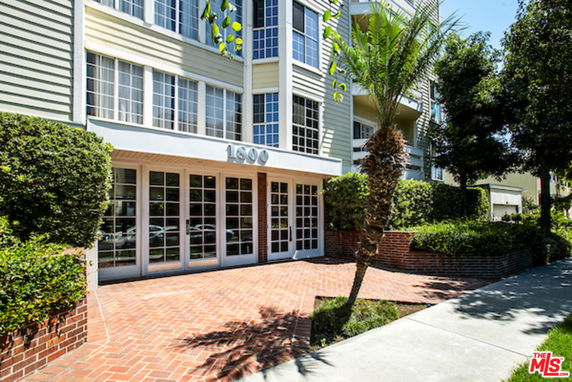 Front view of a multi-story building with glass entrance and brick walkway.