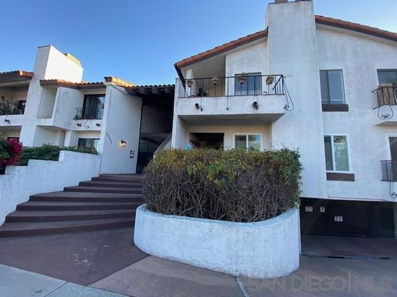 Front view of a multi-story residential building with a white exterior and balconies.