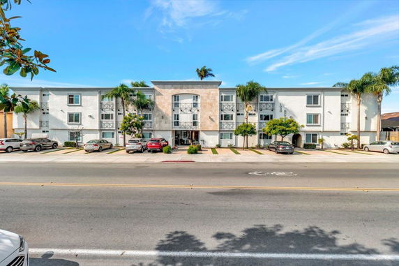 Front view of a multi-story apartment building with a parking area in front.