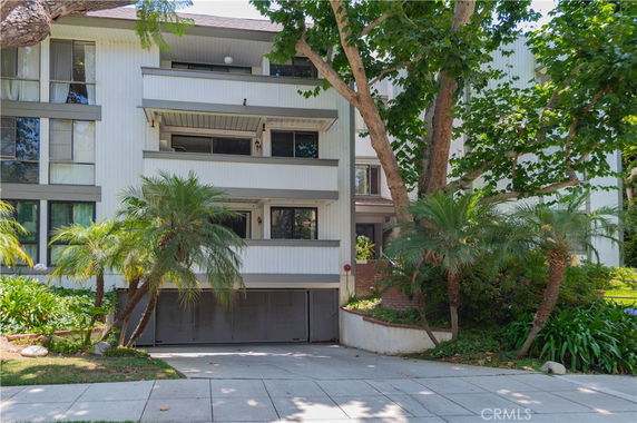 Front view of a multi-story residential building with balconies and a garage entrance.