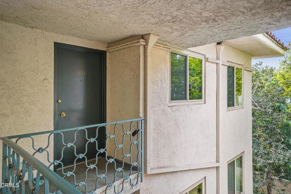 Exterior view of an apartment building's entrance with unit 301 door and railing.