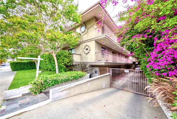 Front view of a multi-story residential building with balconies and a gated entrance.