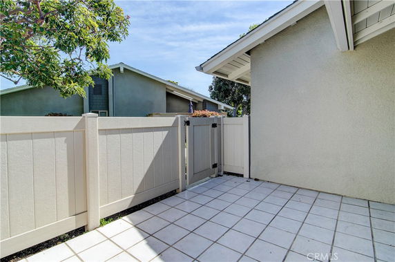 Front view of a building with a tiled patio area and a white fence.