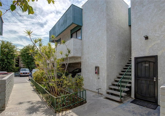 View of a modern multi-story building with outdoor stairs and a dark entrance door labeled G11.