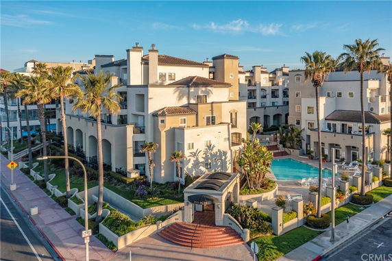 Front view of a multi-story residential building with a swimming pool and palm trees.